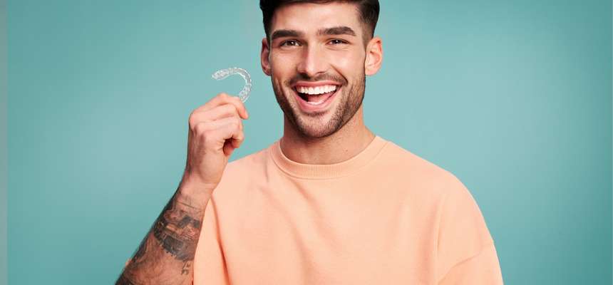 Hombre sonriente sosteniendo un alineador dental DR SMILE