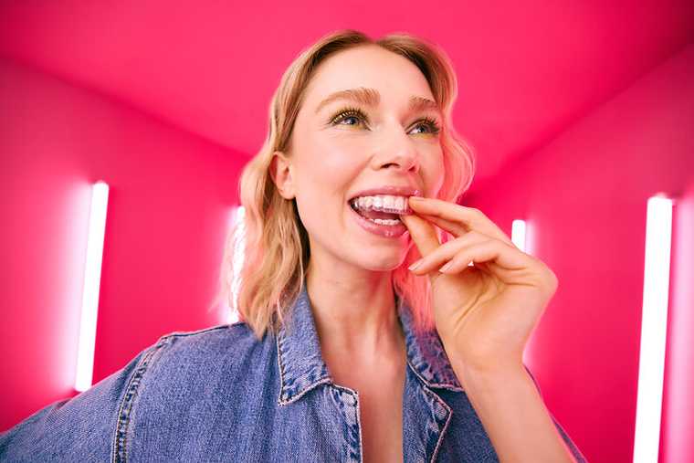 [CRO] Blond - Woman - Aligner - Hand in the teeth - Looking up - Pink - Light - Background - Desktop