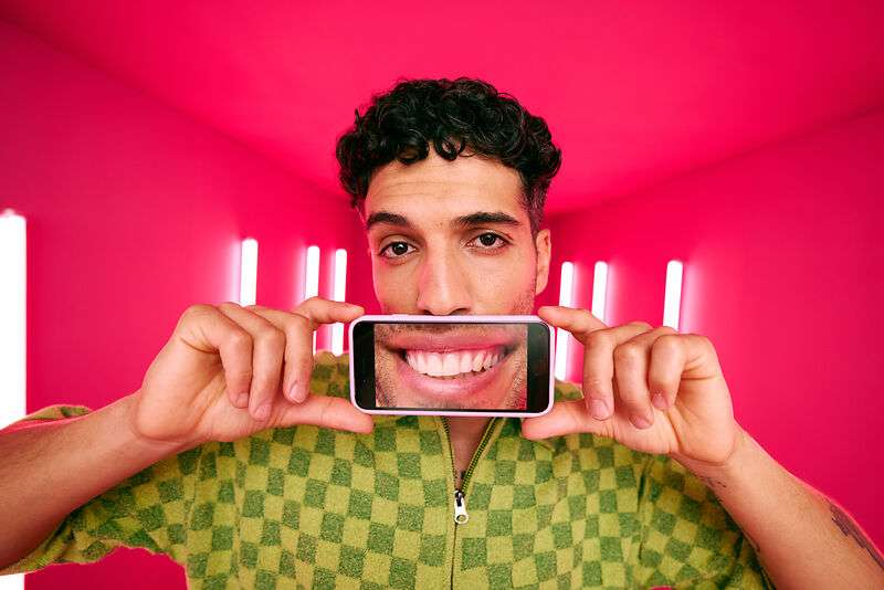 [CRO] Man - Brunette - Curly hair - Smile - Aligner - APP - Blue - Plaid T-shirt - Pink - Light - Background - Desktop